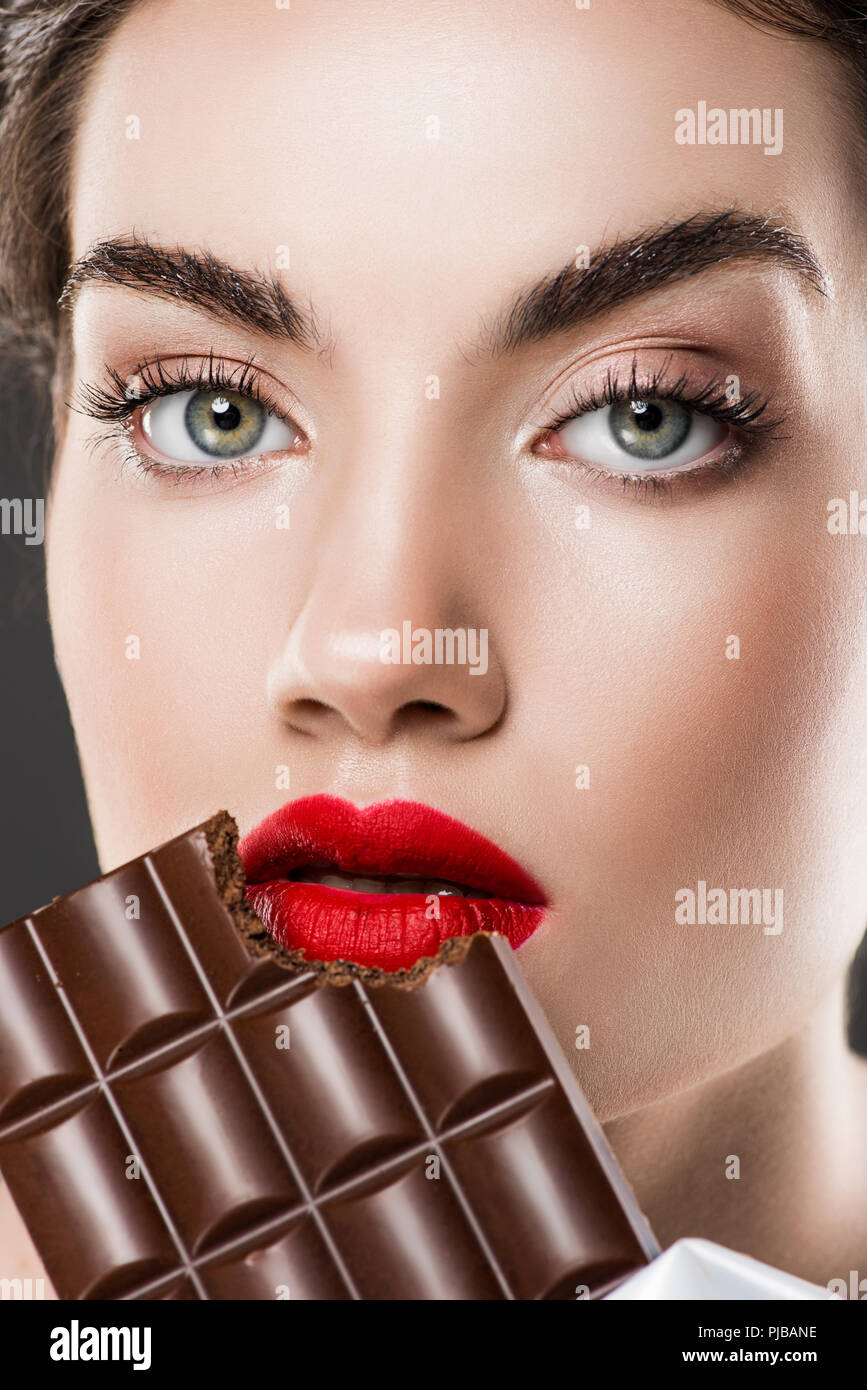 Attractive Girl With Red Lips Eating Chocolate Bar Isolated On Grey attractive-girl-with-red-lips-eating-chocolate-bar-isolated-on-grey