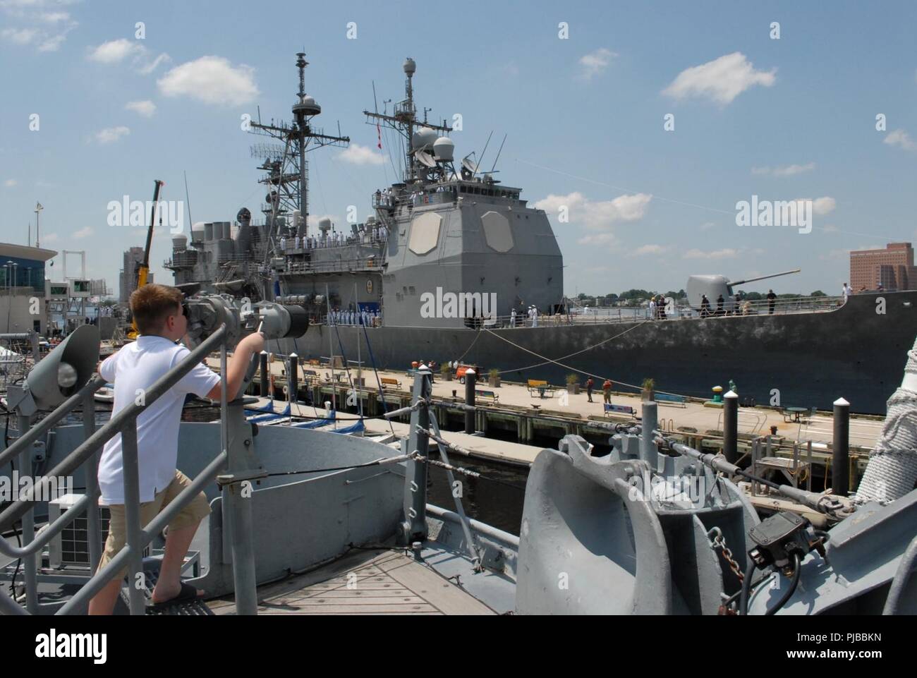 A visitor on-board the USS Wisconsin (BB-64) has a rare opportunity to watch the USS Monterey (CG-61) dock next to the museum ship. The Monterey will be docked behind the Hampton Roads Naval Museum and Nauticus at the Half-Moon cruise ship terminal through July 4, 2018. The Ship's crew will host free tours to the general public starting at 10am through 4pm on July 4, 2018.     The Hampton Roads Naval Museum is one of ten Navy museums that are operated by the Naval History & Heritage Command. It celebrates the long history of the U.S. Navy in the Hampton Roads region of Virginia and is co-locat Stock Photo