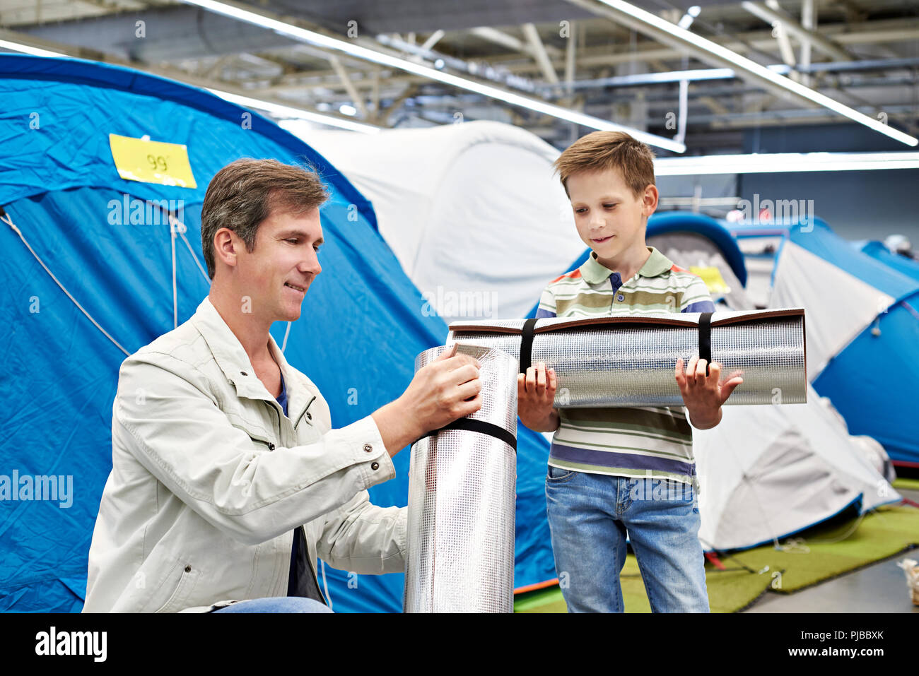 Dad with his son with a tourist camp mat in a sports shop Stock Photo