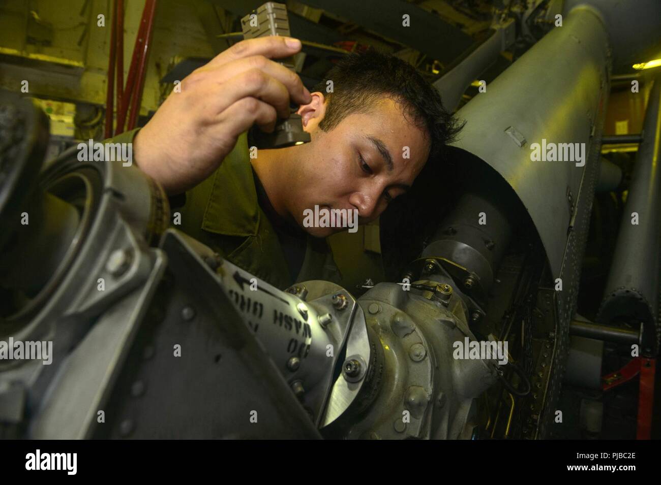 SEA OF JAPAN (July 4, 2018) Aviation Machinist’s Mate 2nd Class Isaac Conrad, from San Diego, performs pre-flight maintenance on a MH-60R Sea Hawk helicopter, assigned to the “Warlords” of Helicopter Maritime Strike Squadron (HSM) 51 in the helicopter hanger of the Ticonderoga-class guided-missile cruiser USS Antietam (CG 54). Antietam is on patrol in the U.S. 7th Fleet area of operation supporting security and stability in the Indo-Pacific region. Stock Photo