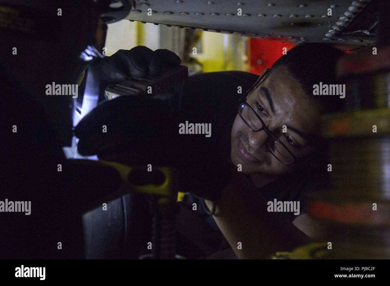 SEA OF JAPAN (July 4, 2018) Aviation Structural Mechanic 2nd Class Steve PortilloBonilla, from Los Angeles, performs pre-flight maintenance on a MH-60R Sea Hawk helicopter, assigned to the “Warlords” of Helicopter Maritime Strike Squadron (HSM) 51 in the helicopter hanger of the Ticonderoga-class guided-missile cruiser USS Antietam (CG 54). Antietam is on patrol in the U.S. 7th Fleet area of operation supporting security and stability in the Indo-Pacific region. Stock Photo