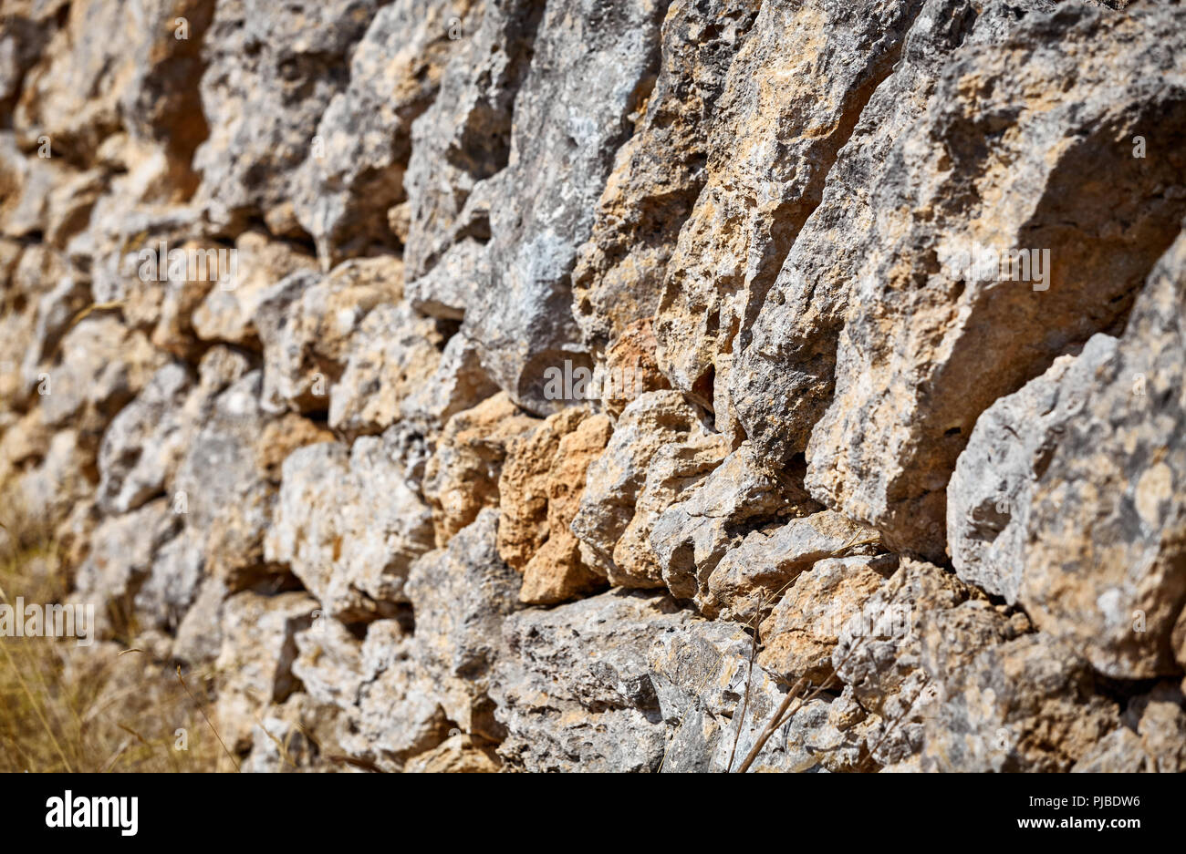 Old wall made of volcanic rough rocks, shallow depth of field. Stock Photo