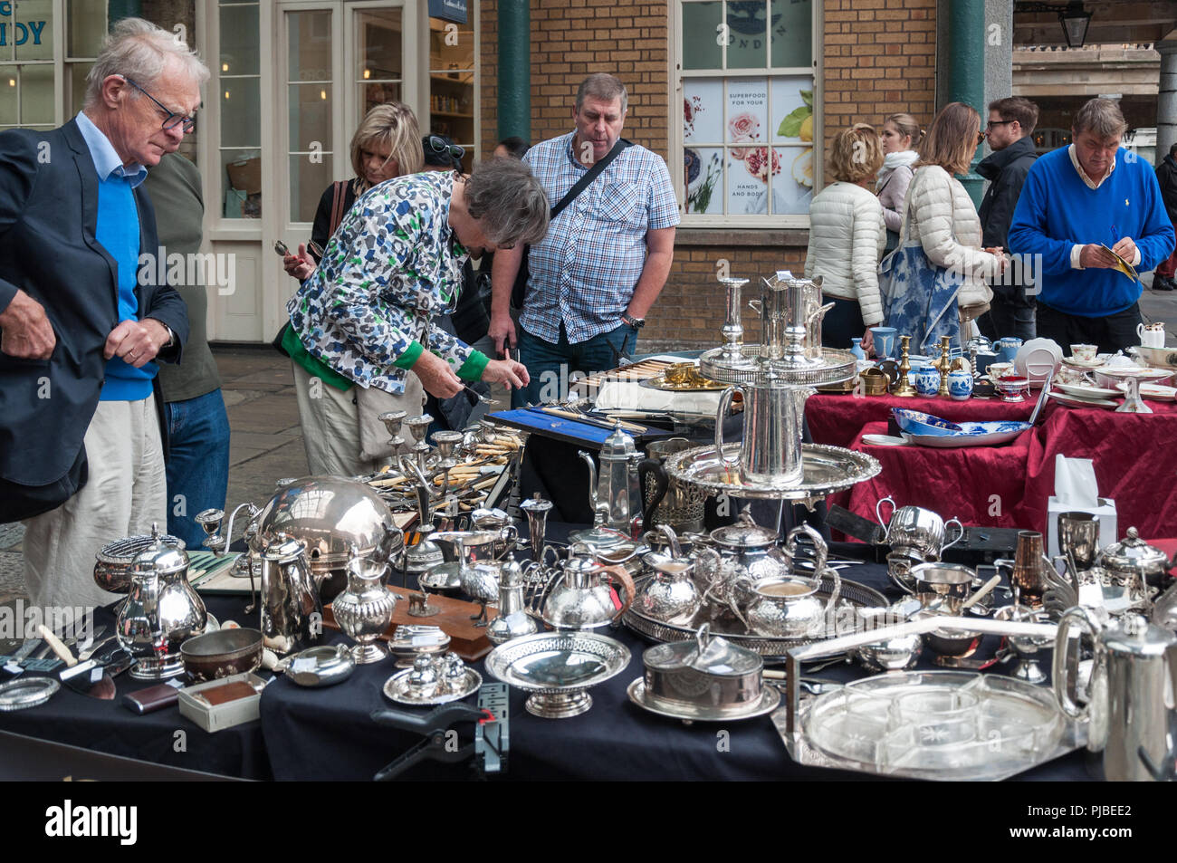 People browsing at a silverware stall in the market, Covent Garden, London, England, UK Stock Photo