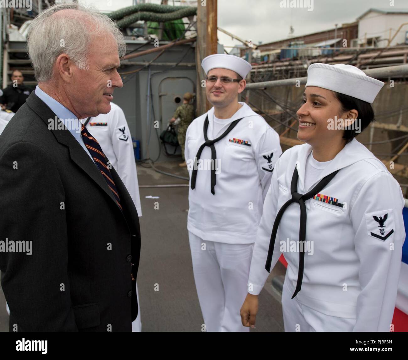 Secretary of the Navy Richard V. Spencer speaks with Musician 3rd Class T'anna Tercero, assigned to the U.S. Seventh Fleet Band, following a ceremony aboard the guided-missile destroyer USS John S. McCain (DDG 56) to induct U.S. Sen. John S. McCain III into the ship's official namesake July 12, 2018. Expanding the namesake to include Senator McCain honors his family's three generations of dedicated service to the U.S. Navy. Stock Photo