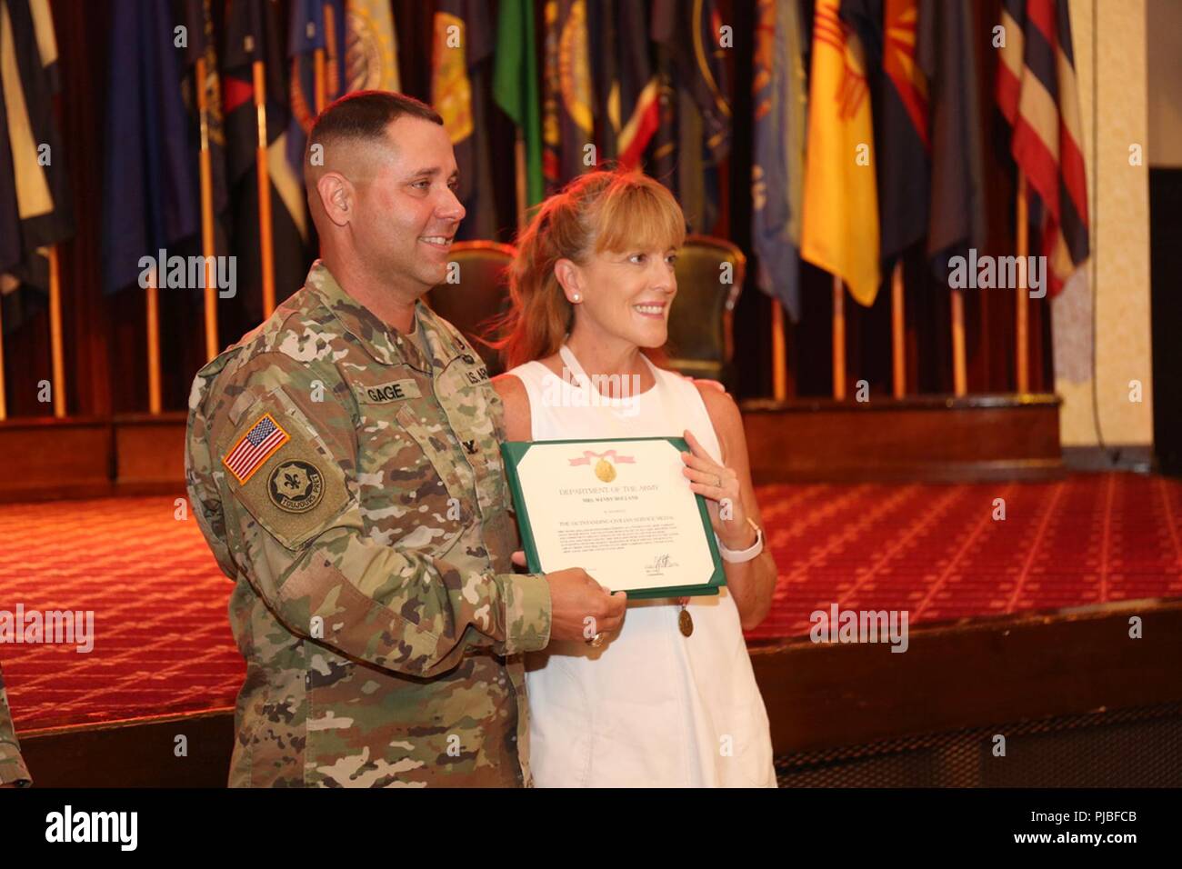 Col. Phillip Gage, USAG Japan commander, presents Wendy Holland with an Outstanding Civilian Service Award for her dedication and volunteerism in the community during an informal ceremony before her husband's relinquishment of responsibility ceremony July 11, 2018, at Camp Zama Community Club.  Her husband, outgoing Command Sgt. Maj. Will Holland, told ceremony attendees that Zama was the best duty station he had served at in his 32-year-career. Stock Photo