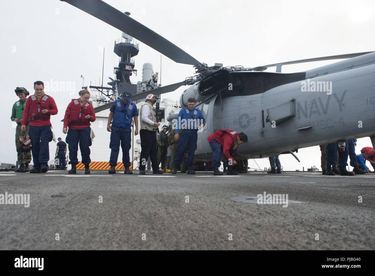 PACIFIC OCEAN (July 10, 2018) Crewmembers aboard the USCGC Bertholf (WMSL 750) check the flight deck July 10, 2018, alongside the flight crew of the a U.S. Navy HSC-4 Black Knight MH-60 helicopter 15 miles south of Oahu, Hawaii, while in support of RIMPAC 2018.  Twenty-five nations, more than 46 ships and 5 submarines, about 200 aircraft and 25,000 personnel are participating in RIMPAC from June 27 to Aug. 2 in and around the Hawaiian Island and Southern California.  The world’s largest international maritime exercise, RIMPAC provides a unique training opportunity while fostering and sustainin Stock Photo
