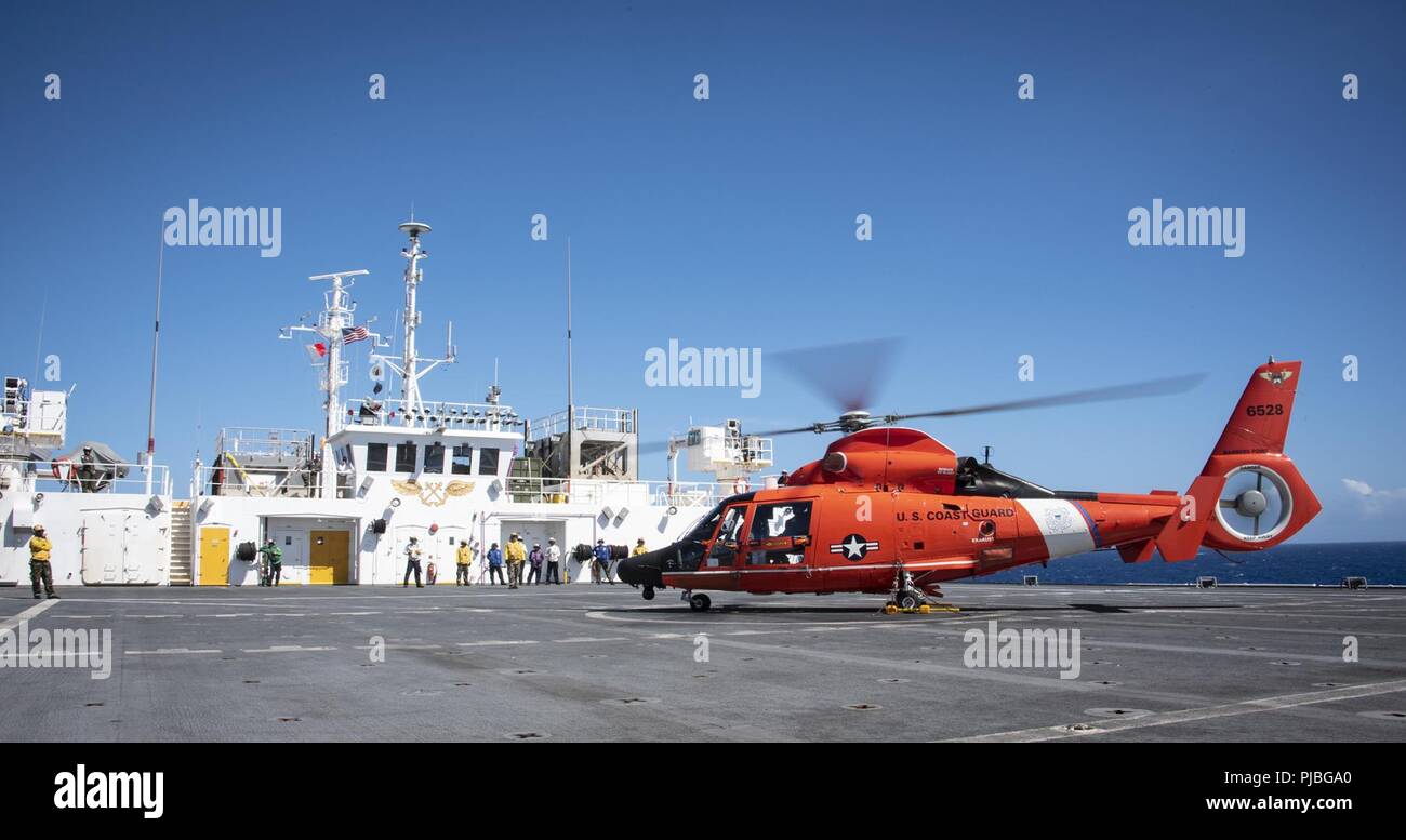 PACIFIC OCEAN (July 11, 2018) An MH-65 Dolphin helicopter from Coast Guard Air Station Barbers Point sits on the flight deck of USNS Mercy (T-AH 19) after completing a medical evacuation exercise during Rim of the Pacific (RIMPAC) exercise. Twenty-five nations, more than 46 ships and 5 submarines, about 200 aircraft and 25,000 personnel are participating in RIMPAC from June 27 to Aug. 2 in and around the Hawaiian Island and Southern California.  The world’s largest international maritime exercise, RIMPAC provides a unique training opportunity while fostering and sustaining cooperative relation Stock Photo