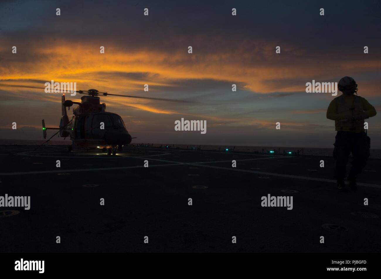 PACIFIC OCEAN (July 10, 2018)  An MH-65 Dolphin helicopter from Coast Guard Air Station Barbers Point, Hawaii, prepares for takeoff July 10, 2018, on the flight deck of the USCGC Bertholf (WMSL 750), 15 miles south of Oahu in support of RIMPAC 2018.  Twenty-five nations, more than 46 ships and 5 submarines, about 200 aircraft and 25,000 personnel are participating in RIMPAC from June 27 to Aug. 2 in and around the Hawaiian Island and Southern California.  The world’s largest international maritime exercise, RIMPAC provides a unique training opportunity while fostering and sustaining cooperativ Stock Photo