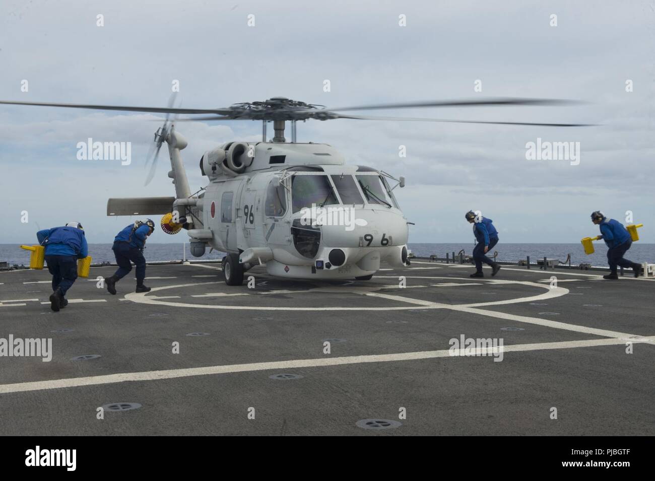 PACIFIC OCEAN (July 11, 2018) Coast Guard flight crew move across the flight deck of the USCGC Bertholf (WMSL 750) July 11, 2018, to secure a helicopter from the Japanese Maritime Self-Defense Force destroyer helicopter ship JS Ise (DDH 182) approximately 15 miles southwest of Oahu, Hawaii, in support of RIMPAC 2018.  Twenty-five nations, more than 46 ships and five submarines, about 200 aircraft and 25,000 personnel are participating in RIMPAC from June 27 to Aug. 2 in and around the Hawaiian Island and Southern California.  The world’s largest international maritime exercise, RIMPAC provides Stock Photo