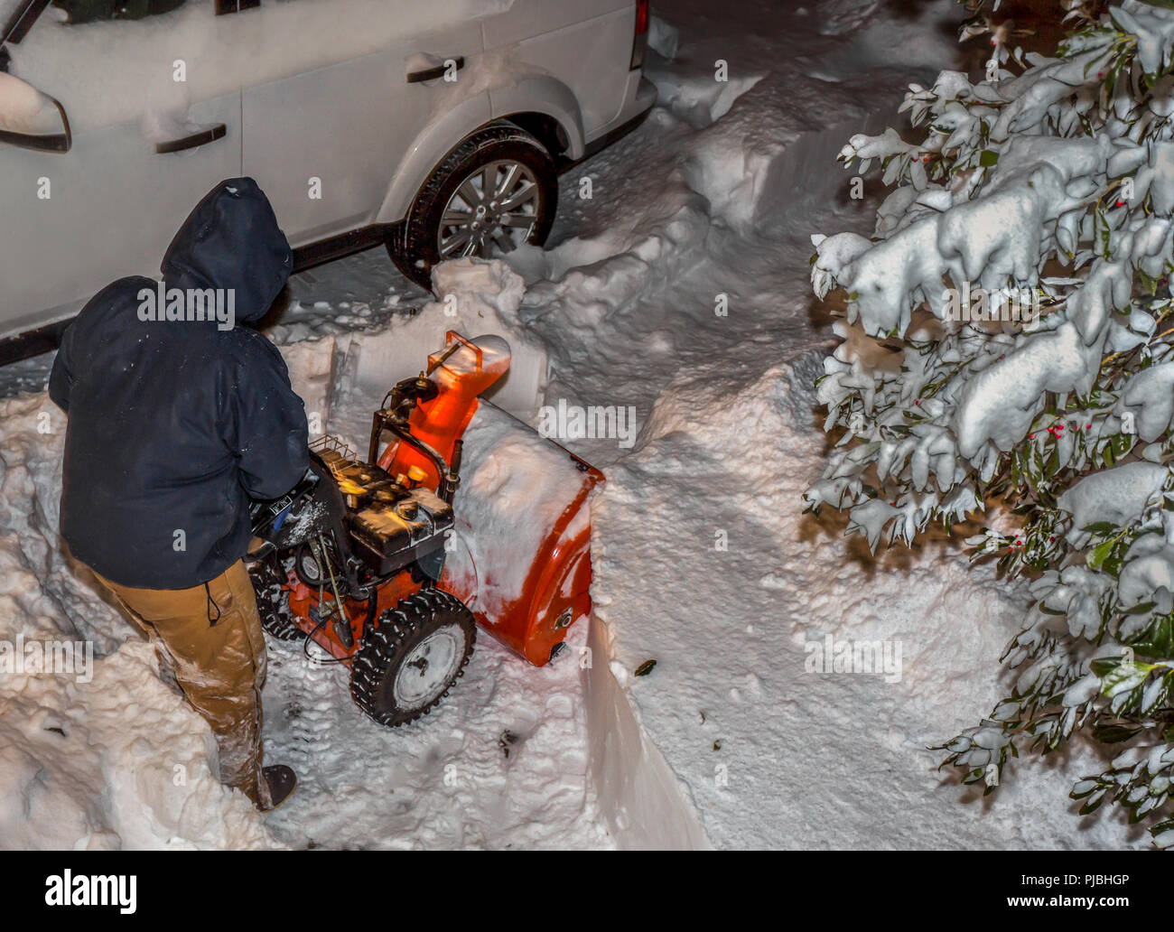 Man clearing his driveway with a snowblower during a blizzard Stock Photo