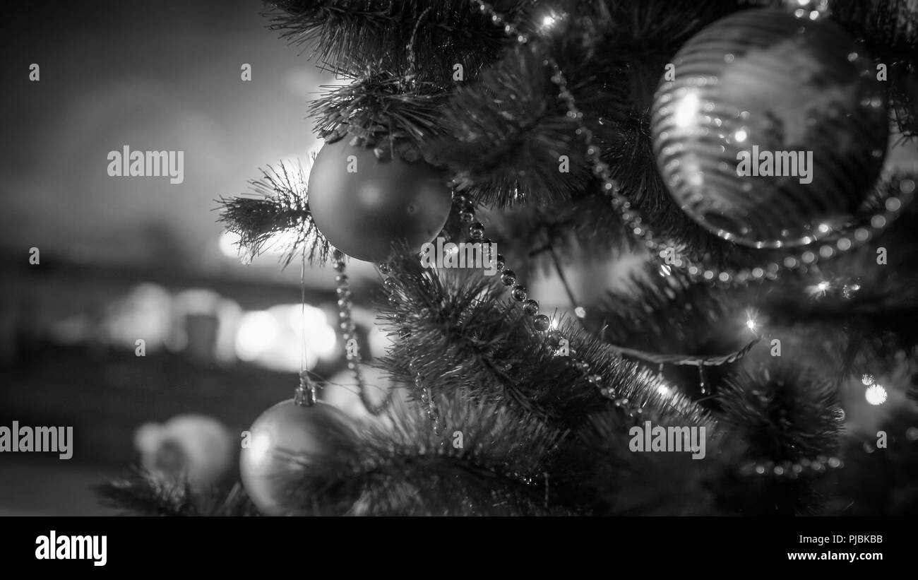 Black and white image of Christmas tree branches with hanging baubles