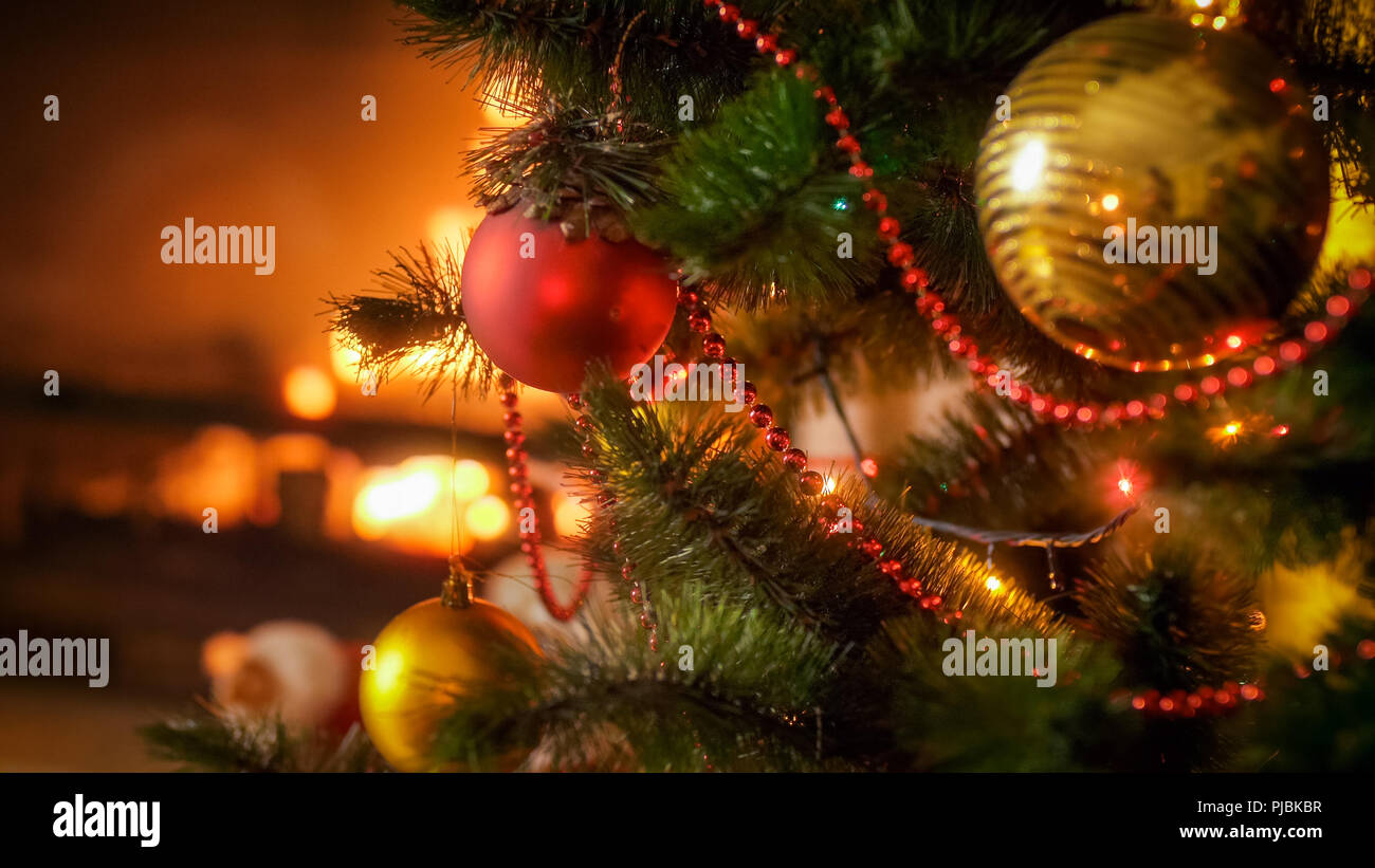Closeup image of beautiful red bauble hanging on decorated Christmas tree at night Stock Photo