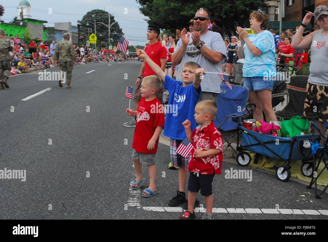 Three boys wave American flags as the 20th CBRNE Command passes by