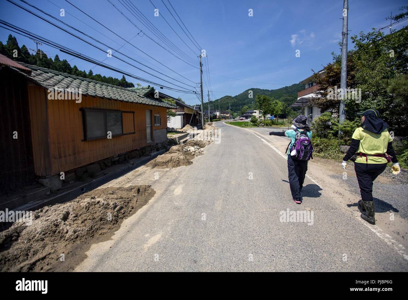 Yasue Fuki and Tomomi Haratani, master labor contractors from Marine Corps Air Station (MCAS) Iwakuni, walk toward a clean up site during a volunteer event in Shuto Town, Iwankuni City, Japan, July 13, 2018. The volunteer event, organized by the Marine Corps Community Services Single Marine Program, provided service members with the opportunity to help local Japanese residents clean up and recover after the area was flooded by excessive rainfall. Stock Photo