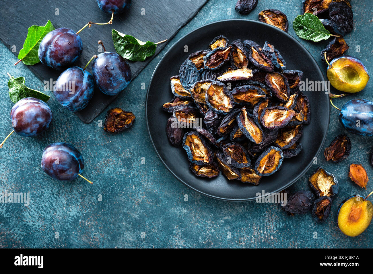 Dried prune and fresh plums with leaves Stock Photo