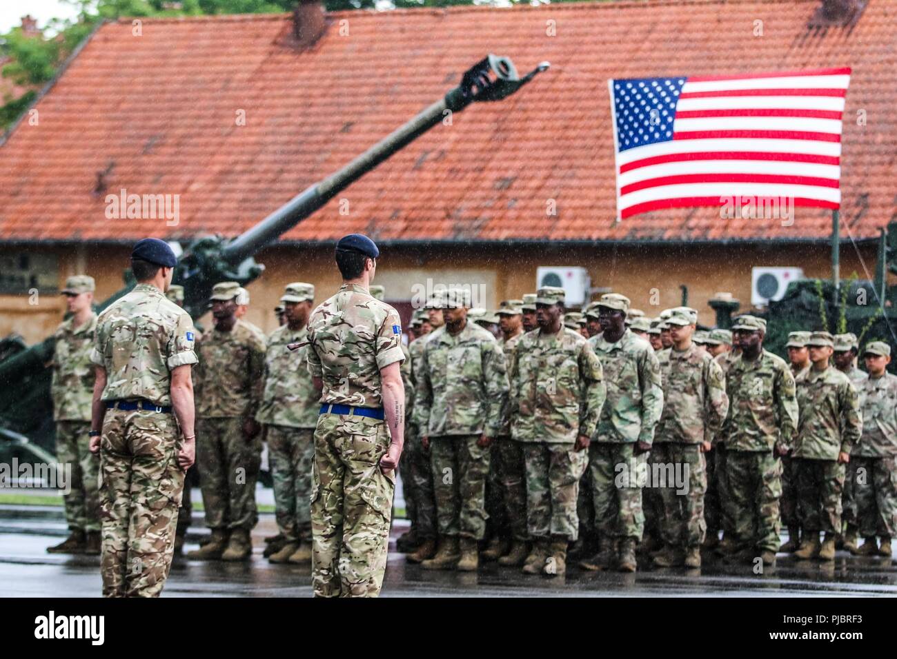 The commander and senior enlisted advisior for the U.K. Army's 1st The Queen's Dragoon Guards (left), stand infront of a formation of U.S. Army Soldiers with 1st Squadron, 2nd Cavalry Regiment, during a change of command ceremony for the Battle Group Poland at Bemowo Piskie Training Area, Poland on July 14, 2018. Battle Group Poland is a unique, multinational coalition of U.S., U.K., Croatian and Romanian Soldiers who serve with the Polish 15th Mechanized Brigade as a deterrence force in support of NATO’s Enhanced Forward Presence. Stock Photo