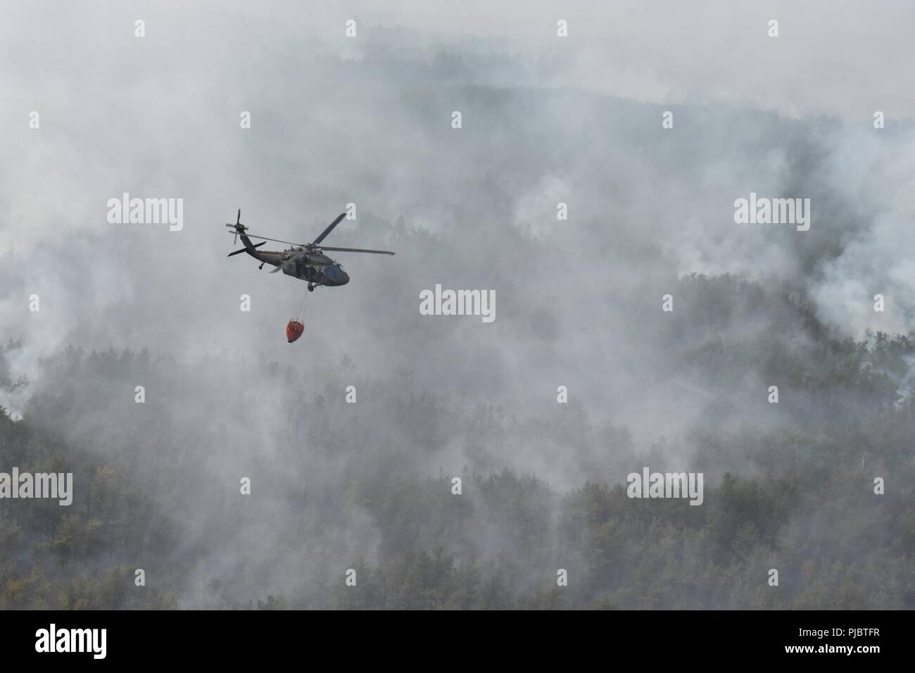 U.S. Soldiers with the 3rd Battalion, 142nd Aviation Regiment, New York Army National Guard fly a UH-60 Black Hawk helicopter over a forest fire in Altona Flat Rock, New York, July 13, 2018. The NYARNG responded to a forrest fire that broke out and spread across hundreds of acres from July 13-15. Stock Photo