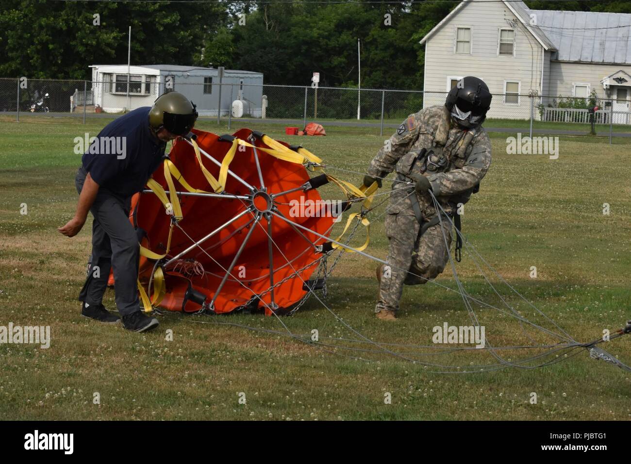 New York Army National Guard Staff Sgt. Jimmy Rose(right), assigned to 3rd Battalion, 142nd Aviation , and civilian Steven Rosen, load a Bambi bucket onto a UH-60 Blackhawk Helicopter in Altona , N.Y., July, 13, 2018. Two UH-60 aircrews  responded to a forest fire that broke out in Altona, N.Y., and spread across five hundred of acres, from July 13-15.  Army Guard aircrews flew more missions in support of fire fighters on July 15. (N.Y. Army National Guard Stock Photo