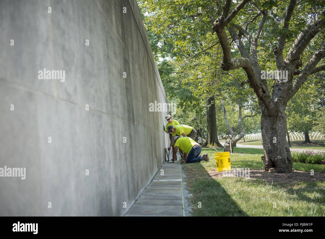 Volunteers straighten, level and replace broken stones outside of Columbarium Court 1 at Arlington National Cemetery, Arlington, Virginia, July 16, 2018. Over 400 volunteer landscape professionals participated in the National Association of Landscape Professionals’ 22nd annual Renewal and Remembrance event at Arlington National Cemetery. Volunteers aerated turf, planted flowers, laid irrigation pipes, and installed lighting protection on several trees. Stock Photo