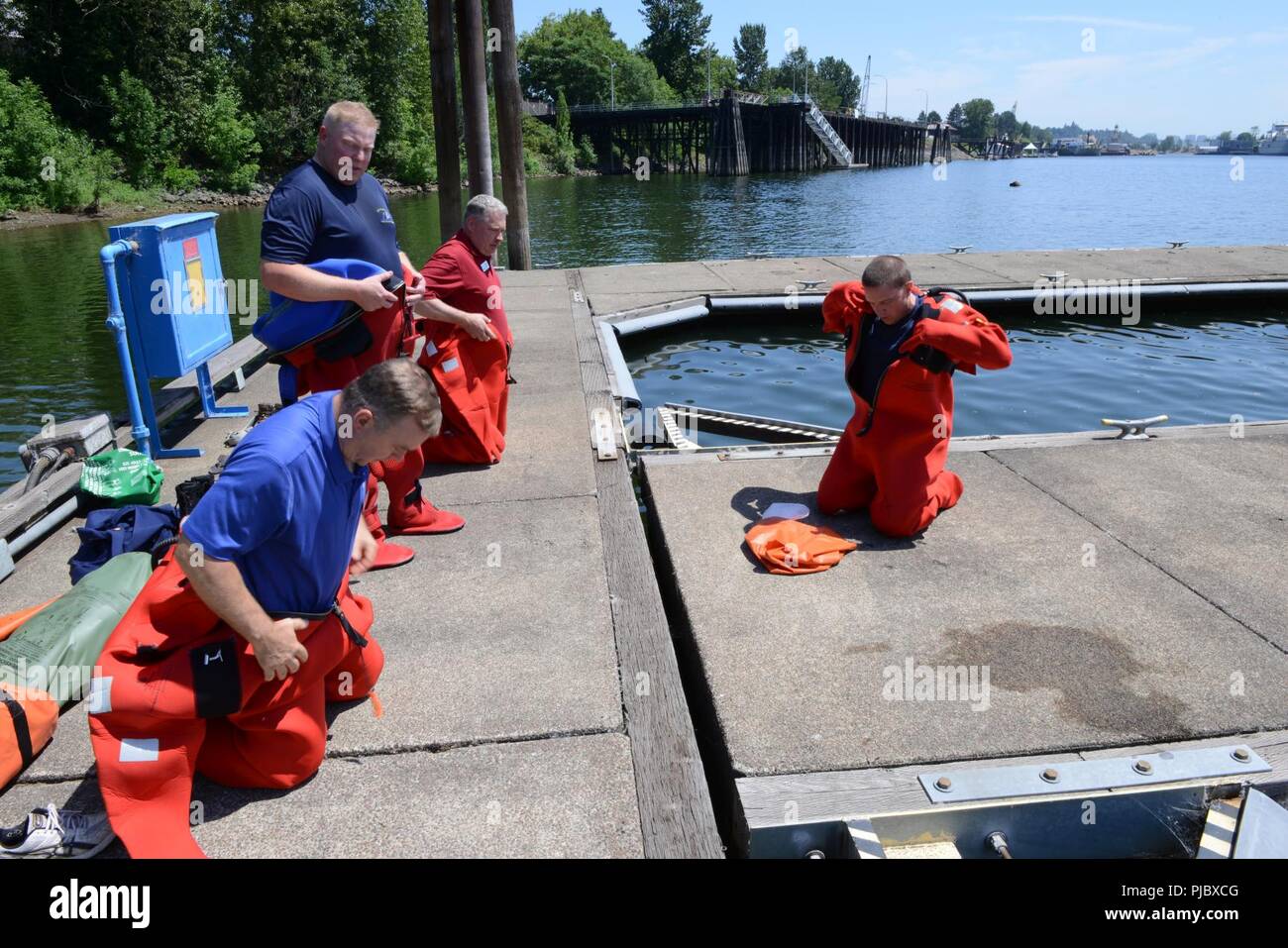 Mike Rudolph, a fishing vessel safety examiner at Marine Safety Unit Portland, instructs the donning of a Type V immersion survival suits to members of the Washington Homeland Security Roundtable at MSU Portland, Ore., July 16, 2018.    The training helps members of WHSR understand some of the safety measures taken to insure survival of mariners at sea.     U.S. Coast Guard Stock Photo