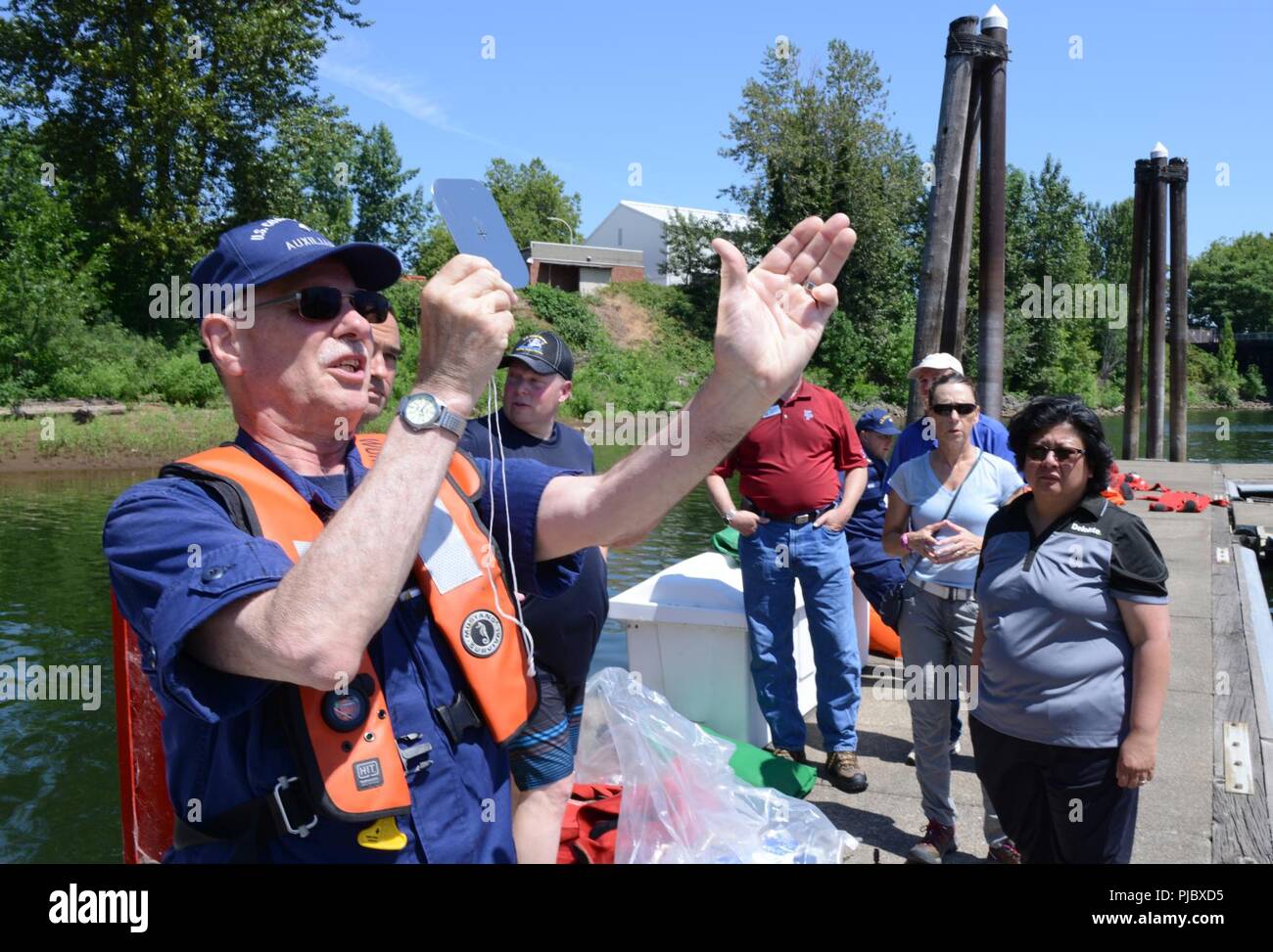 Ron Hilburger, a Coast Guard Auxiliary sector coordinator, demonstrates how to use a signal mirror for members of the Washington Homeland Security Roundtable visiting Marine Safety Unit Portland, Ore., July 16, 2018.    An emergency signal mirror is a device used to signal potential search and rescue assets at extremely long distances.     U.S. Coast Guard Stock Photo