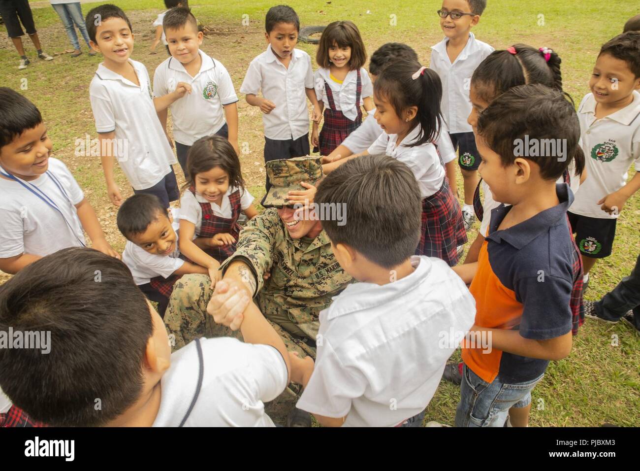 U.S. Marine Staff Sgt. Jesse Braswell, the command element company gunnery sergeant with Special Purpose Marine Air-Ground Task Force – Southern Command, plays with local Guatemalan children during a site survey at a school Marines will be refurbishing in Flores, Guatemala, July 9, 2018. The Marines and sailors of SPMAGTF-SC are conducting security cooperation training and engineering projects alongside partner nation military forces in Central and South America. The unit is also on standby to provide humanitarian assistance and disaster relief in the event of a hurricane or other emergency in Stock Photo