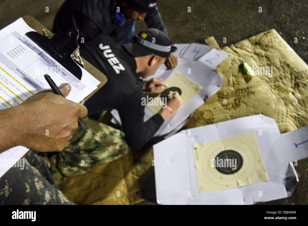 Fuerzas Comando graders check targets after a stress-shoot preceded by a 20-kilometer ruck march during Fuerzas Comando, July 17, 2018 at the Instituto Superior Policial, Panama. Fuerzas Comando is an annual multinational special operational forces skills competition sponsored by U.S. Southern Command and hosted this year by the Ministry of Public Security, Panama. Through friendly competition, this exercise promotes interoperability, military-to-military relationships, increases training knowledge, and improves regional security. Stock Photo