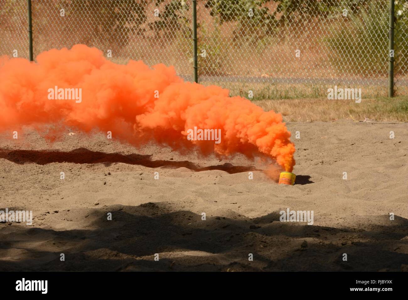 Orange smoke billows out of a canister during an emergency flare