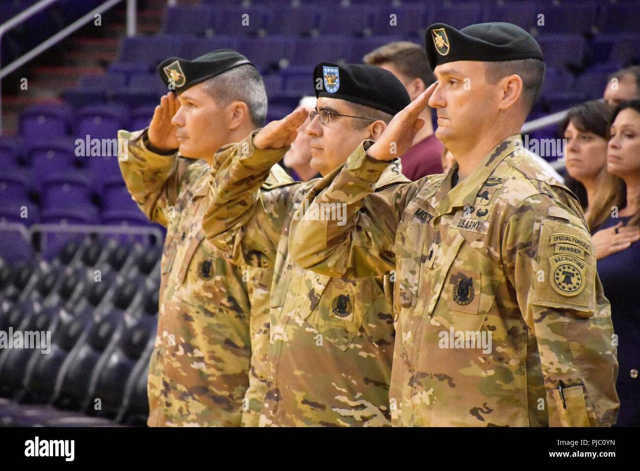 Lt. Col. Dave Clukey (left), outgoing commander, Phoenix Recruiting Battalion, Col. Roman Cantu (center), commander, 5th Recruiting Brigade, and Lt. Col. K. Scott Morley (left), incoming commander, Phoenix Rec. Bn., salute during the playing of the national anthem, prior to a change of command ceremony, July 19, Talking Stick Resort Arena, Phoenix. Stock Photo