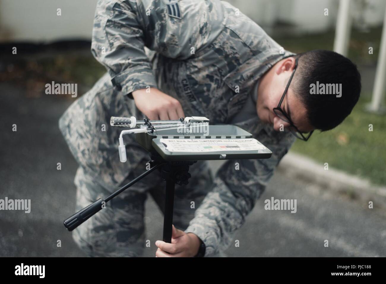 U.S Air Force Senior Airman Rodulfo Castro, 18th Aerospace Medical Squadron bioenvironmental engineering technician, inspects a manual Wet Bulb Globe Temperature Meter July 19, 2018, at Kadena Air Base, Japan.  The temperatures taken are used to determine the current flag conditions for the entire installation. Stock Photo