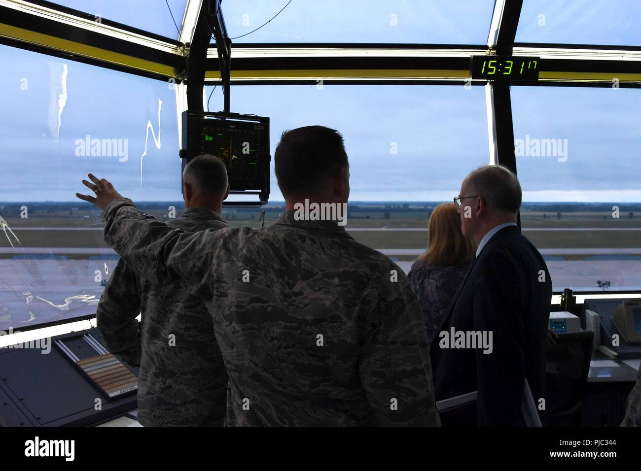 Dominic Pohl, 25th Air Force executive director, right, observes the base geography and flight line through the air traffic control tower windows July 20, 2018, on Grand Forks Air Force Base, North Dakota. Air traffic controllers shared their day-to-day operations with Pohl, detailing how they manage the air space and communicate with aircraft. Stock Photo