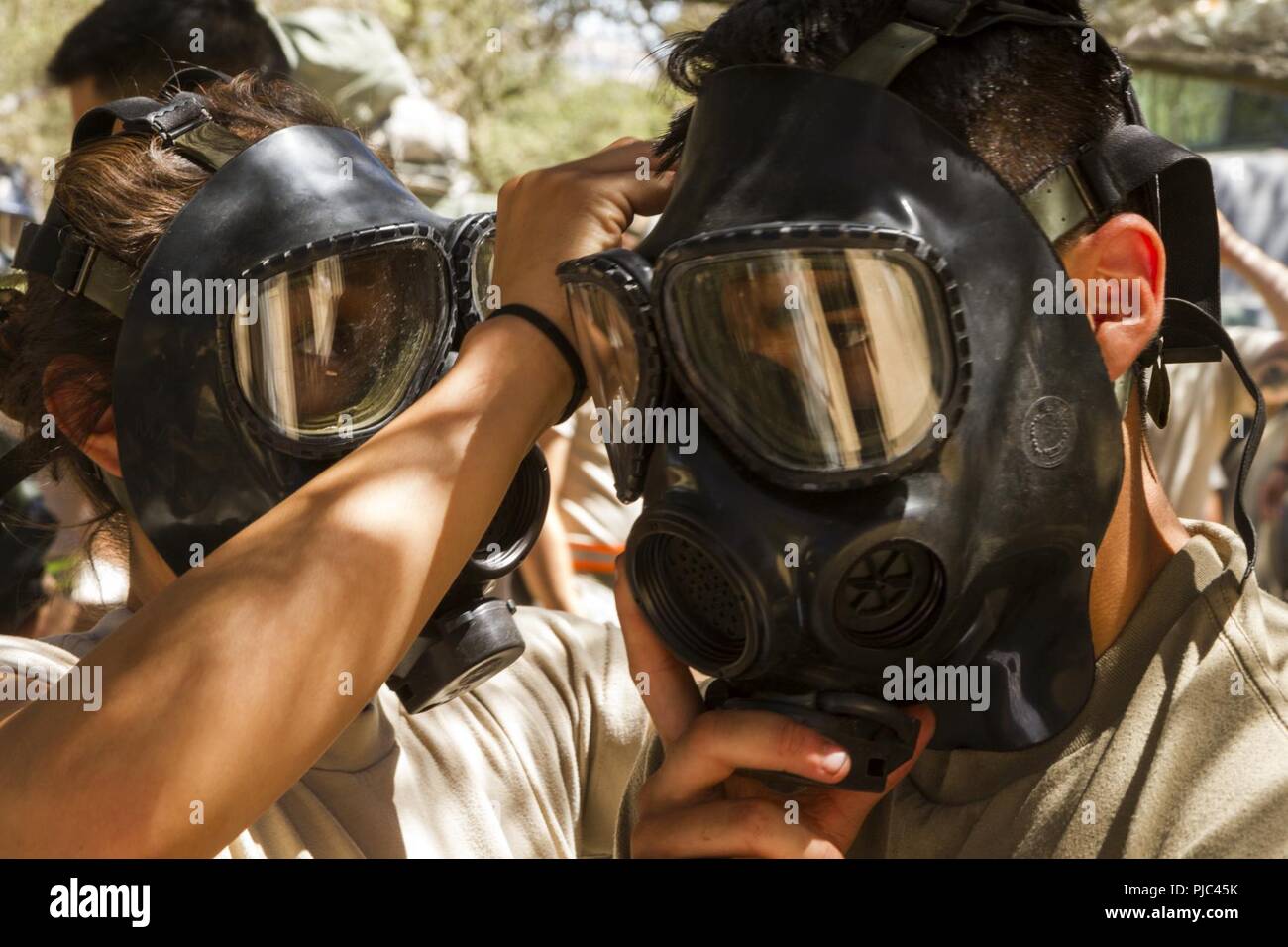 FORT HUNTER LIGGETT-- U.S. Army Spcs. Destini Faulks and Victor Moreno of the 348th Transportation Company put on gas masks in response to a training scenario during the 91st Training Division's Combat Support Training Exercise (CSTX 91-18-01) on July 11, 2018 in Ft. Hunter Liggett, California. The CSTX 91-18-01 ensures America’s Army Reserve units are trained to deploy bringing capable, combat-ready, and lethal firepower in support of the Army and our joint partners anywhere in the world. Stock Photo