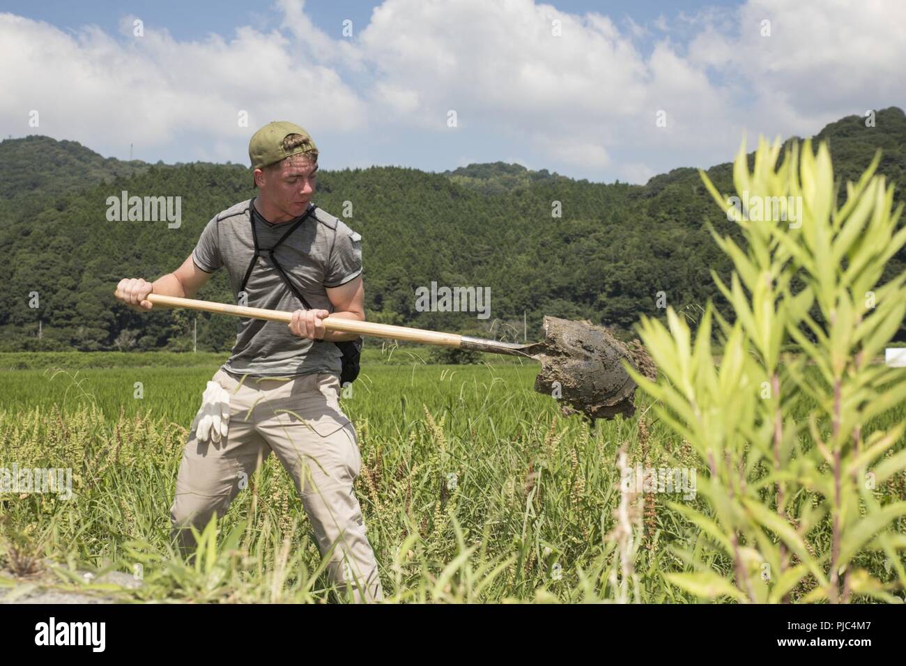 U.S. Marine Corps Lance Cpl. Samuel Bilbey, an ordnance technician with Marine Fighter Attack Squadron 121, shovels mud and debris during a volunteer event at Shimo-nakazone, Shuto in Iwkauni City, Japan, July 14, 2018. The volunteer event, organized by the Marine Corps Community Services Single Marine Program, provided service members with the opportunity to help local Japanese residents clean up and recover after the area was flooded by excessive rainfall. Stock Photo