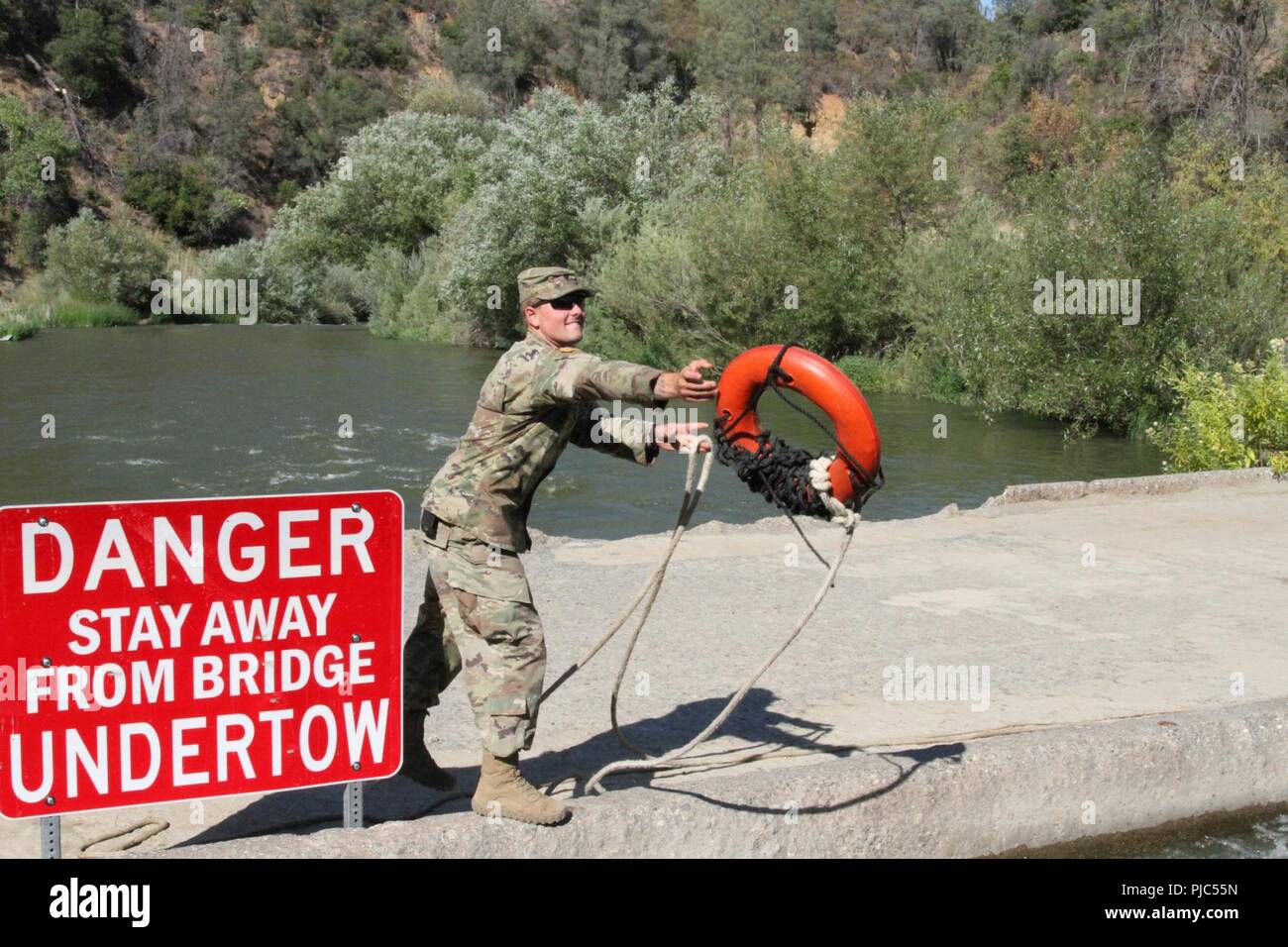 U.S. Army Spc. Christian Berg of the 132nd Multirole Bridge Company, 579th Engineer Battalion, 49th Military Police Brigade, California Army National Guard, tosses a floatation device to a teammate July 13 as members of the 132nd secure a temporary floating bridge at Cache Creek Regional Park, California. The Guardsmen built the bridge so California Department of Forestry and Fire Protection (CAL FIRE) personnel and vehicles have quicker access to fighting wildfires. Stock Photo