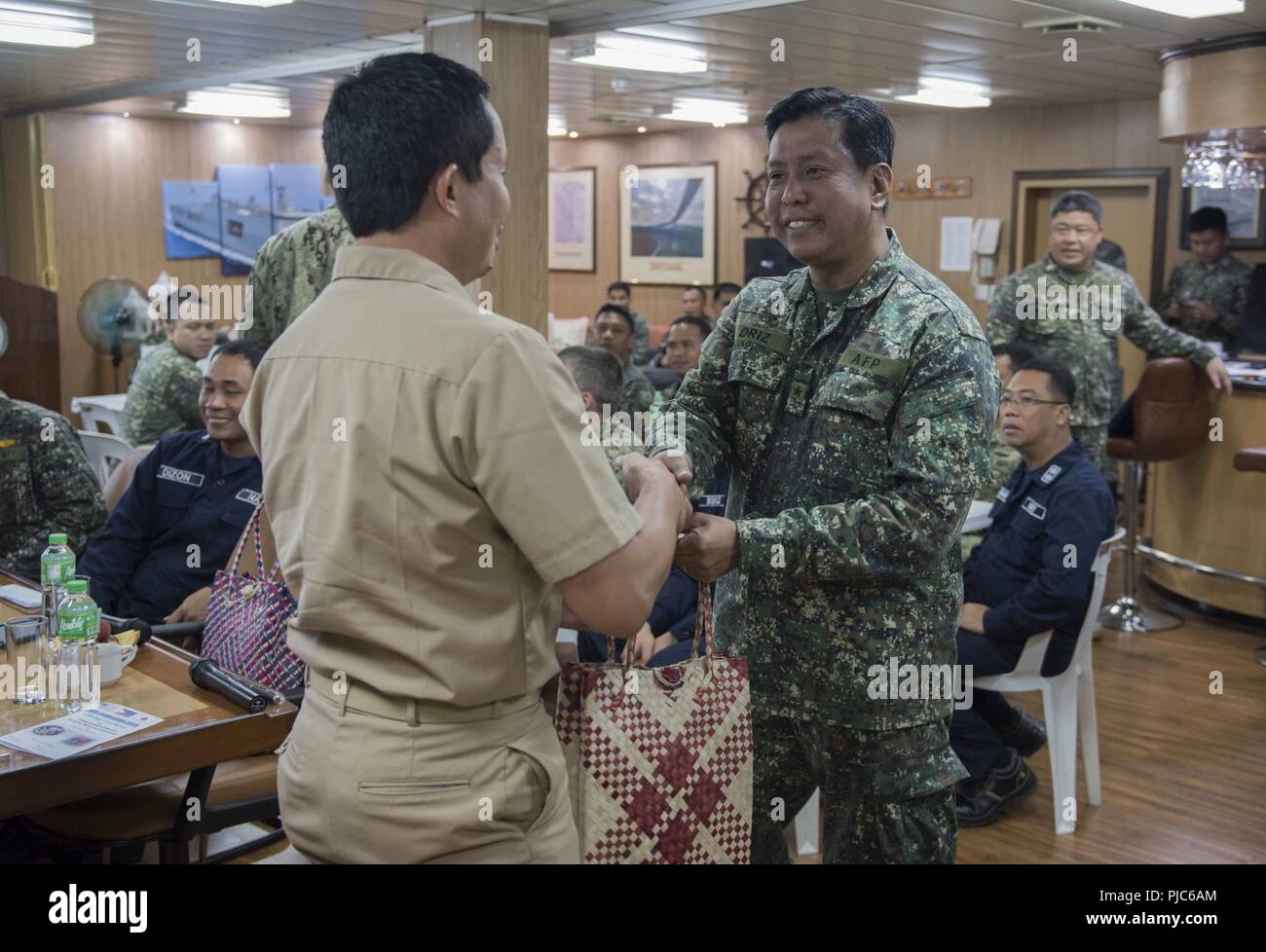 SAN FERNANDO CITY, Philippines (July 14, 2018) Captain Erwin Lao, commanding officer of USNS Millinocket (T-EPF 3), exchanges gifts with Philippine Navy Commodore Nichols Driz, Commander, Naval Forces Northern Luzon, at the closing ceremony of Maritime Training Activity (MTA) Sama Sama 2018 aboard Philippine Navy ship BRP Tarlac (LD-601). The week-long engagement focuses on the full spectrum of naval capabilities and is designed to strengthen the close partnership between both navies while cooperatively ensuring maritime security, stability and prosperity. Stock Photo