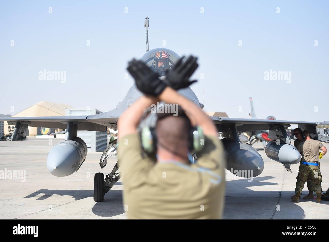 Tech. Sgt. Jeremy Harris, 157th Expeditionary Fighter Squadron crew chief, marshals an F-16 Fighting Falcon onto the ramp after arriving at the 407th Air Expeditionary Group, July 16, 2018, at an undisclosed location in Southwest Asia. More than 300 Airmen from the 169th Fighter Wing of the South Carolina Air National Guard arrived to support of Operation Inherent Resolve. Stock Photo