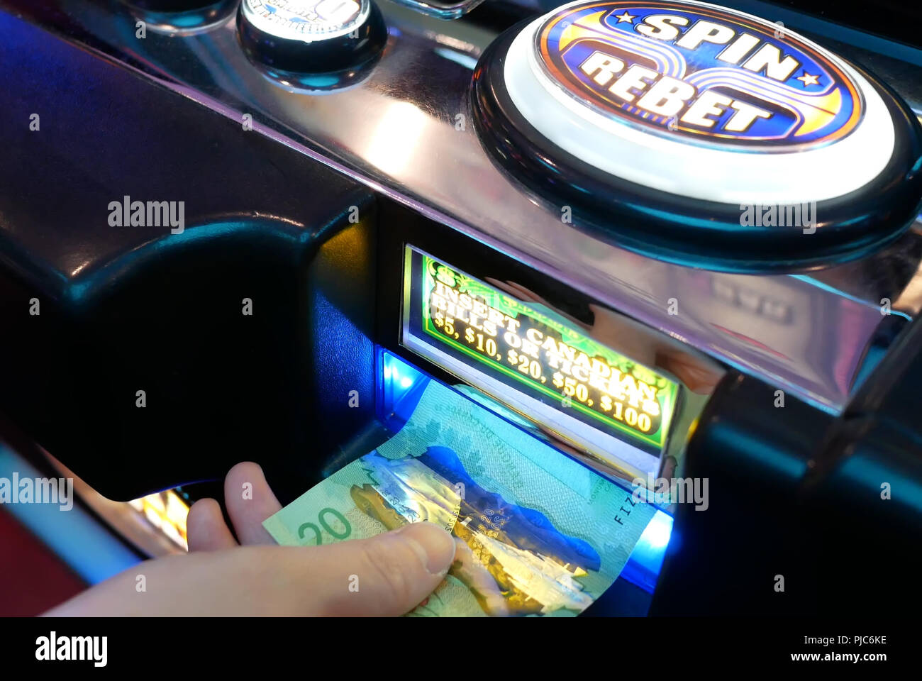 Coquitlam, BC, Canada - June 12, 2018 : Motion of woman inserts money on slot machine inside Casino Stock Photo