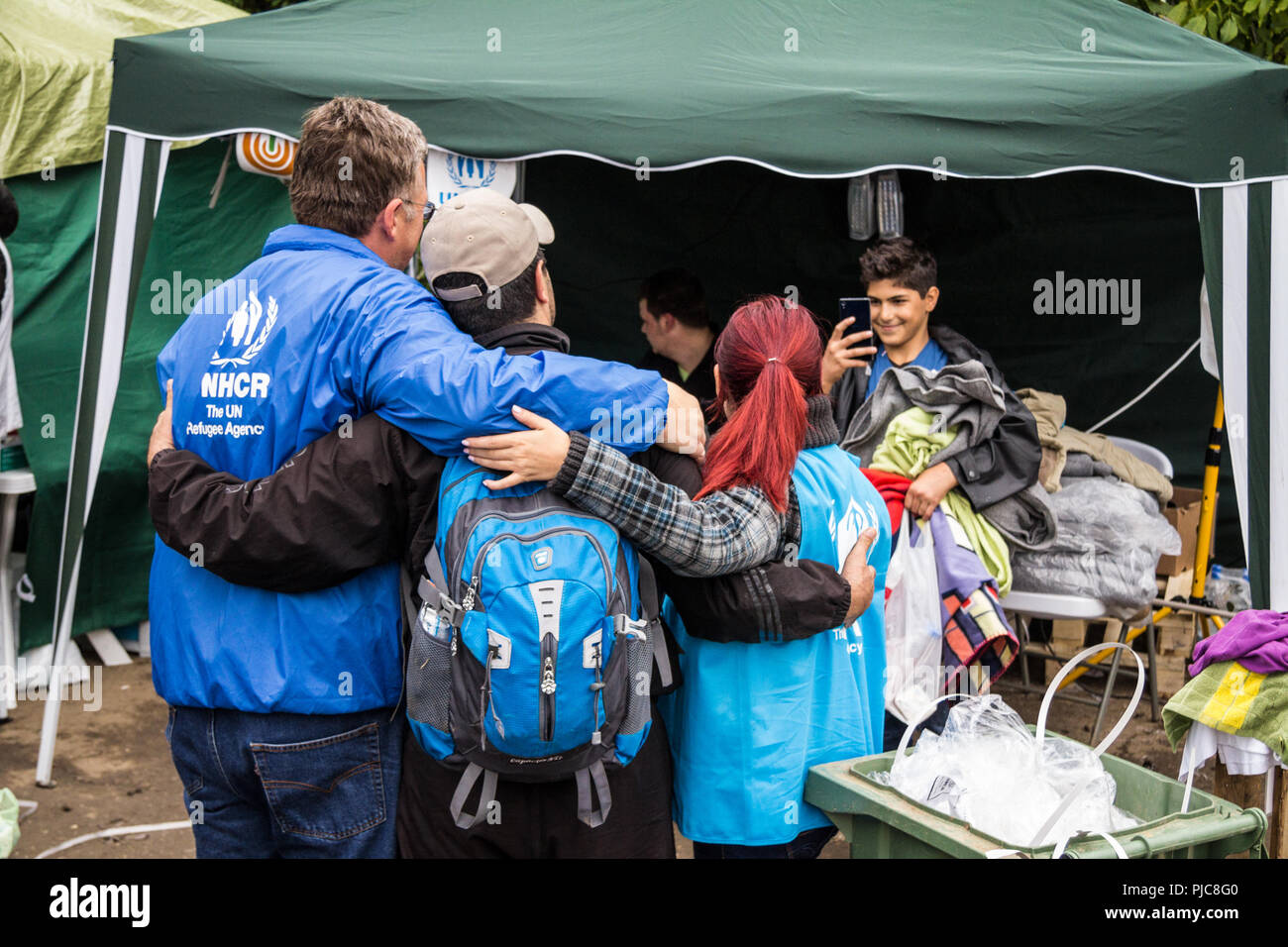 BERKASOVO, SERBIA - SEPTEMBER 27, 2015: Workers of the UNHCR, the United Nations Agency for refugees, taking pictures with a migrant at the border bet Stock Photo