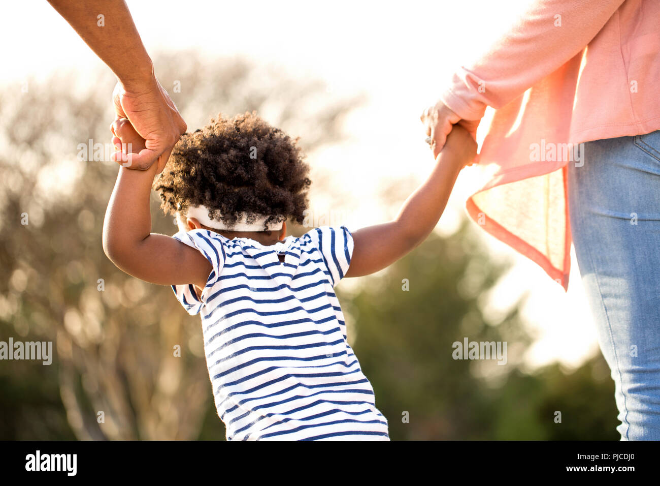 Little girl holding hands with her parents. Stock Photo
