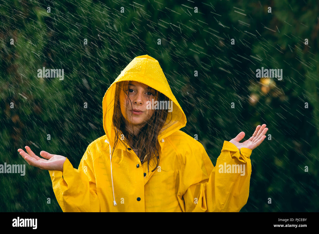 little girl out in the rain with yellow raincoat Stock Photo