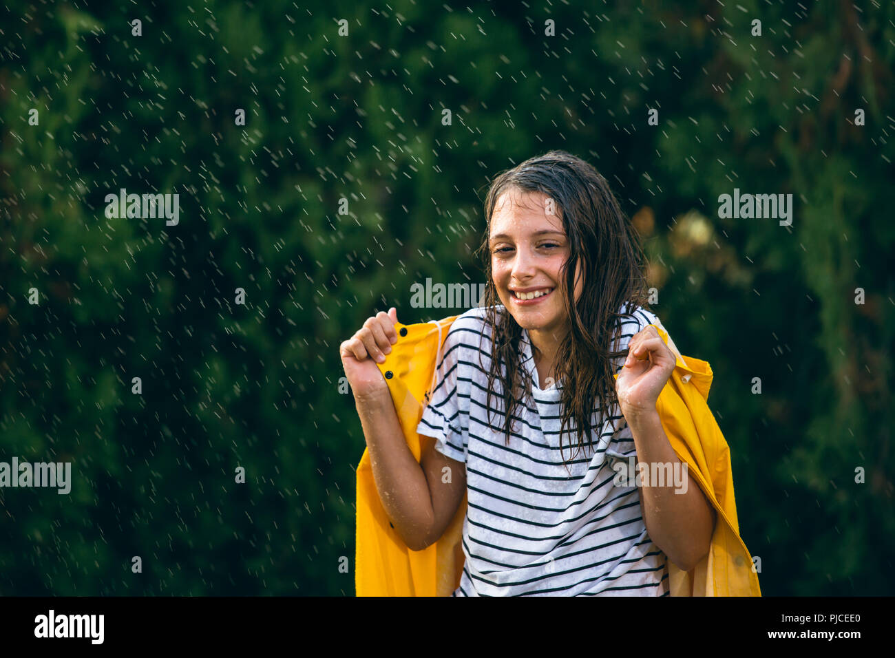 girl with yellow raincoat in rain Stock Photo