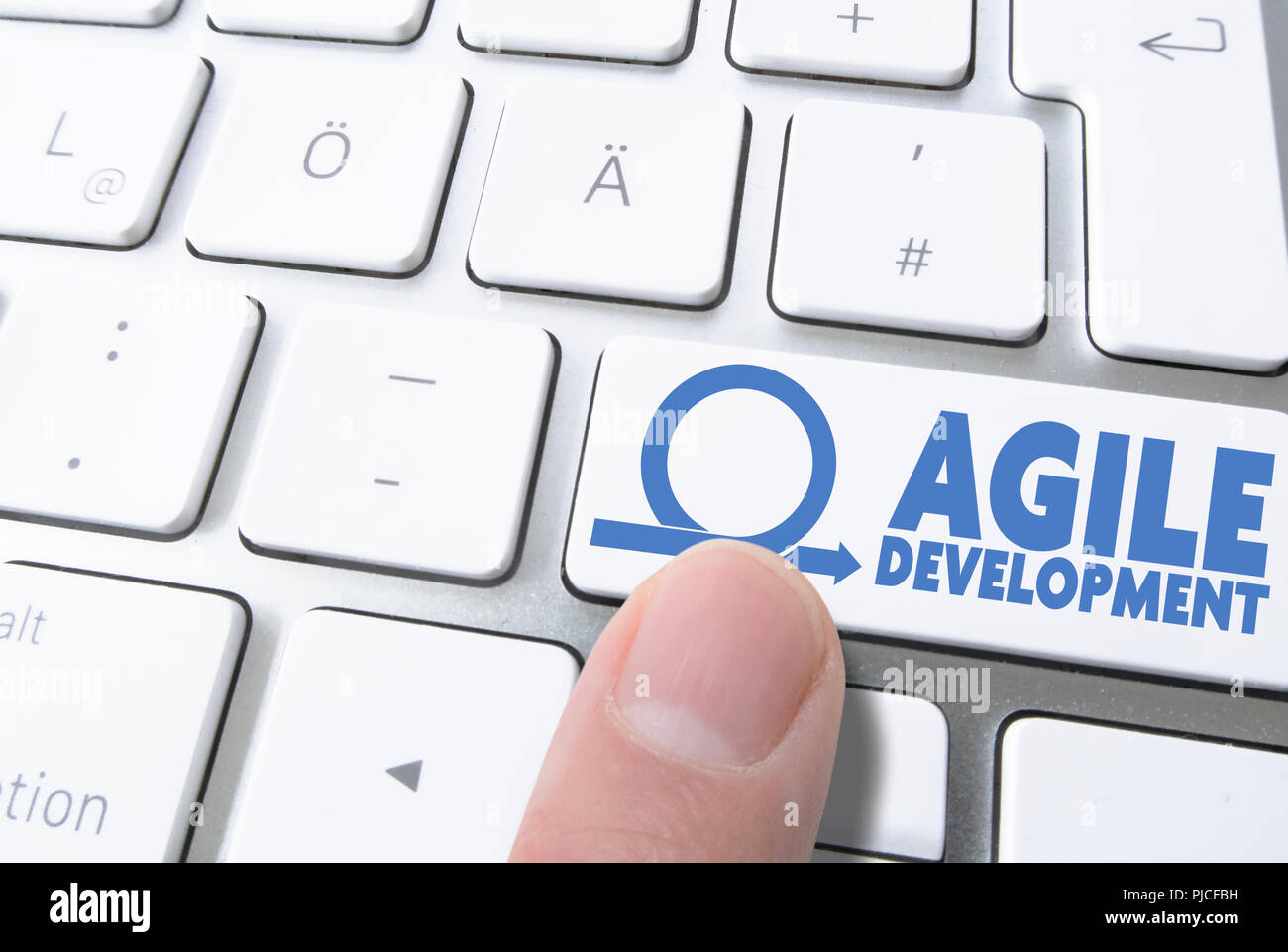 finger pressing key labeled AGILE DEVELOPMENT on computer keyboard Stock Photo