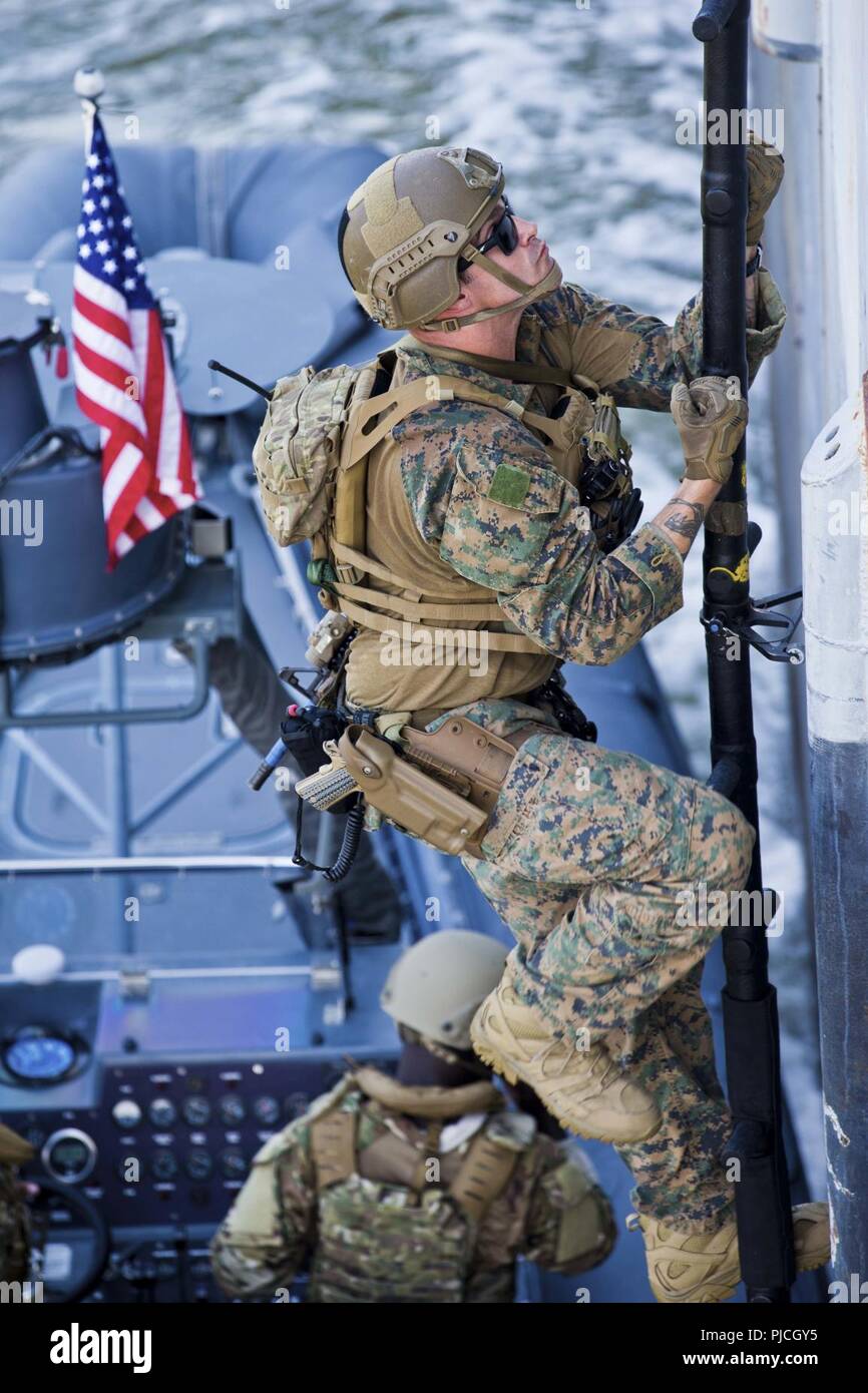 A Special Amphibious Reconnaissance Corpsman with the Maritime Raid Force, 22nd Marine Expeditionary Unit, climbs a Rapid Entry Boarding System (REBS) ladder during a Visit, Board, Search and Seizure course at Fort Eustis, VA, July 11, 2018. This course gives the MRF the capability of launching VBSS operations during the 22nd MEU’s upcoming deployment. Stock Photo