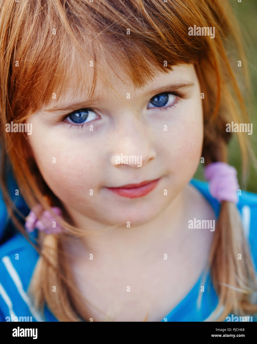 Closeup portrait of cute adorable little red-haired Caucasian girl child with blue eyes looking in camera. Happy childhood  concept Stock Photo