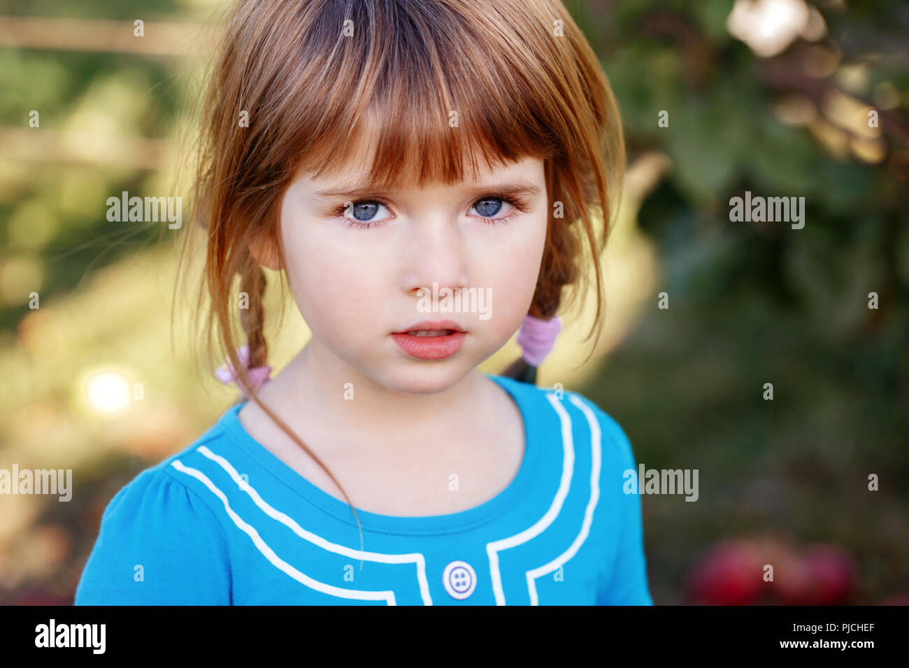 Closeup portrait of cute adorable little red-haired Caucasian girl child with blue eyes looking in camera. Happy childhood  concept Stock Photo