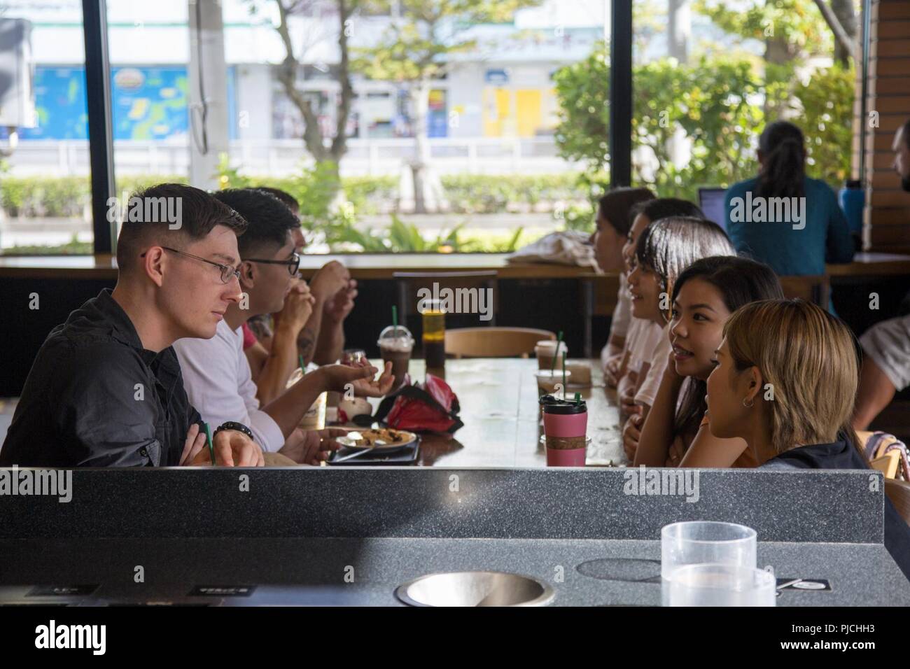 CHATAN, OKINAWA, Japan- Marines from Camp Foster converse with members of the local community during a conversational English class July 18 in Chatan, Okinawa, Japan. The U.S. Consulate General in Naha organizes the meetings through their social media sites, inviting anyone who wants to test out their English speaking skills. The Single Marine Program works together with the U.S. Consulate to bring the local community and Marines together at four locations across the island bimonthly. Stock Photo