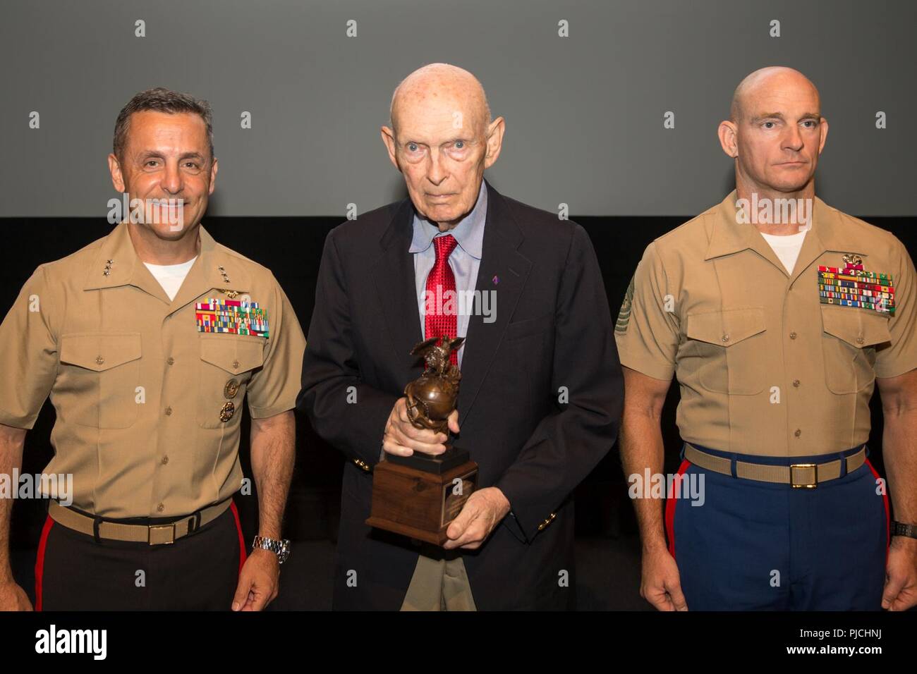 U.S. Marine Corps Lt. Gen. Michael A. Rocco, left, deputy commandant, Manpower and Reserve Affairs, presents James Gillcrist, center, his induction trophy during the 2018 United States Marine Corps Sports Hall of Fame Induction Ceremony at the National Museum of the Marine Corps, Triangle, Va., July 18, 2018. The event was held for the induction of it’s three newest members; James A. Gillcrist, Theodore A. Lyons, and Richard L. Alderson. Stock Photo