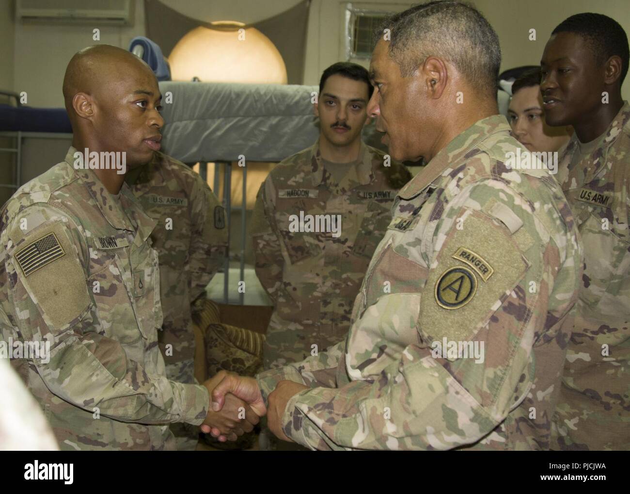 U.S. Army Lt. Gen. Michael X. Garrett, U.S. Army Central (USARCENT) commanding general, awards a coin to U.S. Army Pfc. Kenneth Brown assigned to Headquarters and Headquarters Battery, 3rd Battalion, 2nd Air Defense Artillery Regiment, 31st Air Defense Artillery Brigade during a visit of their unit area, July 22, 2018. Lt. Gen. Garrett visited the battalion as part of his battlefield circulation, which enhances his understanding of the units and Soldiers subordinate to USARCENT. Stock Photo