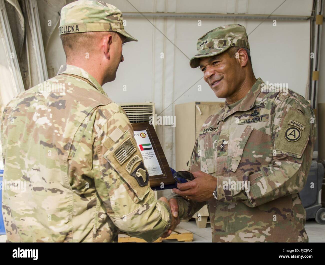U.S. Army Lt. Gen. Michael X. Garrett, U.S. Army Central (USARCENT) commanding general, receives a certificate of appreciation and a flag from U.S. Army 1st Lt. Aaron Hrdlicka assigned to Delta Battery, 3rd Battalion, 2nd Air Defense Artillery Regiment, 31st Air Defense Artillery Brigade, July 22, 2018. Lt. Gen. Garrett visited the battalion as part of his battlefield circulation, which enhances his understanding of the units and Soldiers subordinate to USARCENT. Stock Photo