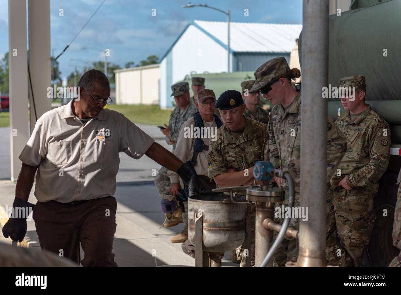 U.S. and British Soldiers observe a member of the Naval Supply Systems Command as a fuel sample is drawn for testing at Naval Air Station Jacksonville following the delivery from the Defense Fuel Support Point in North Jacksonville during the Quartermaster Liquid Logistics Exercise on July 18, 2018. The QLLEX is a multi-component, joint exercise involving elements from the Army Reserves, Defense Logistics Agency and the United States Navy to transport petroleum from a supply hub to the end user, in this case Navy Aviation. ( Stock Photo